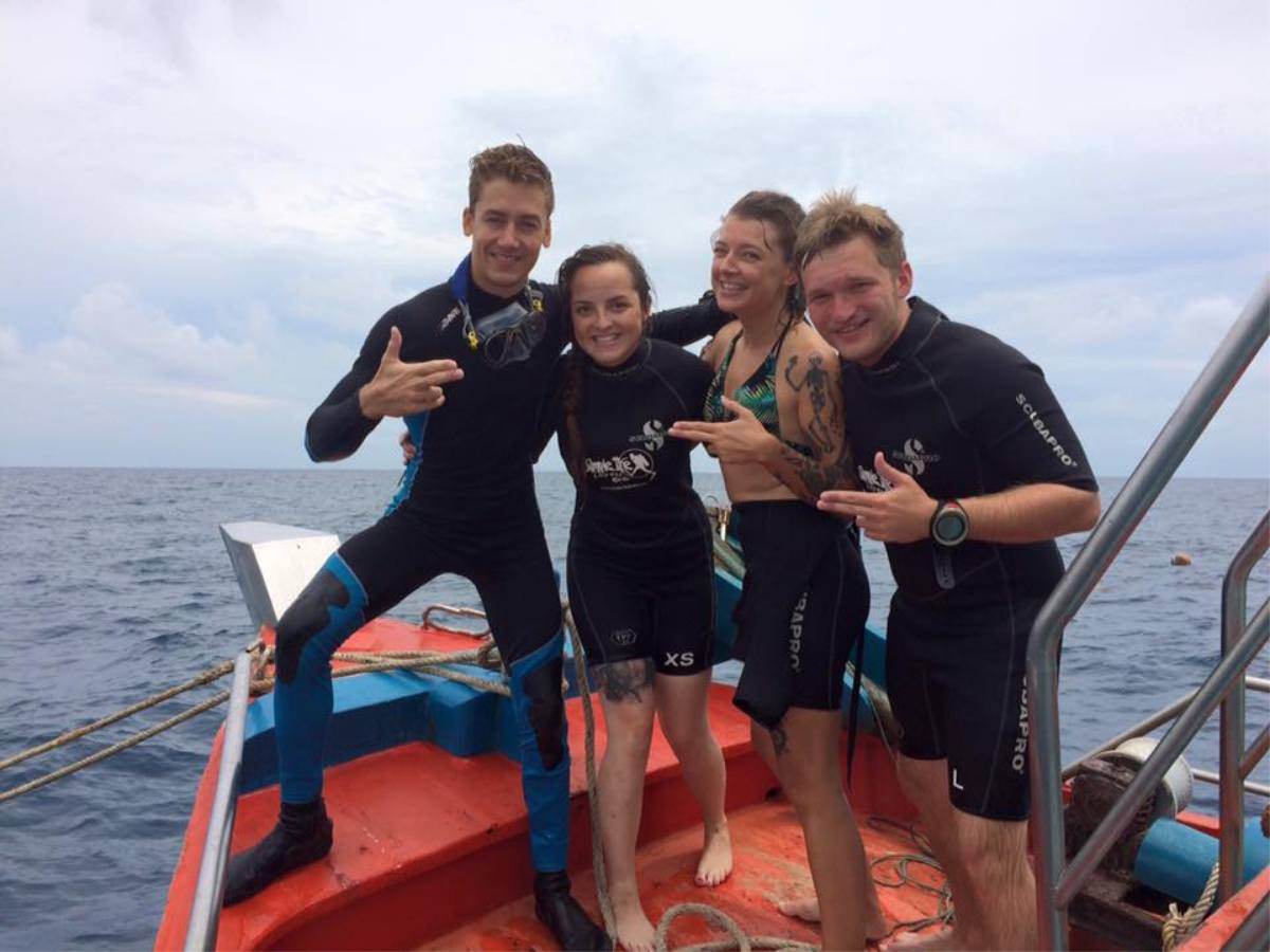 An image of 4 people in wetsuits on a boat in Thailand