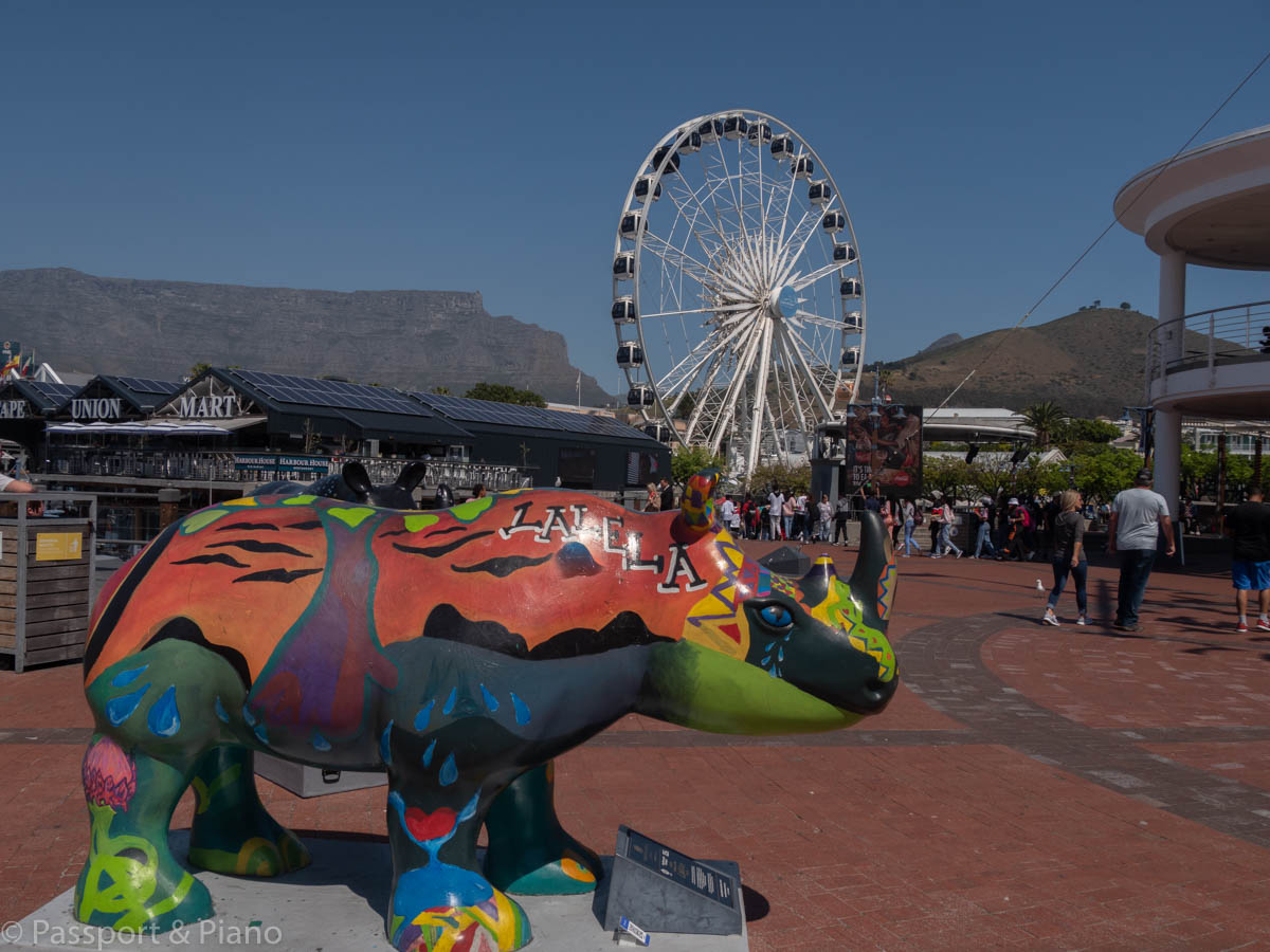 An image of a coloured rhino with the Cape Wheel behind it.