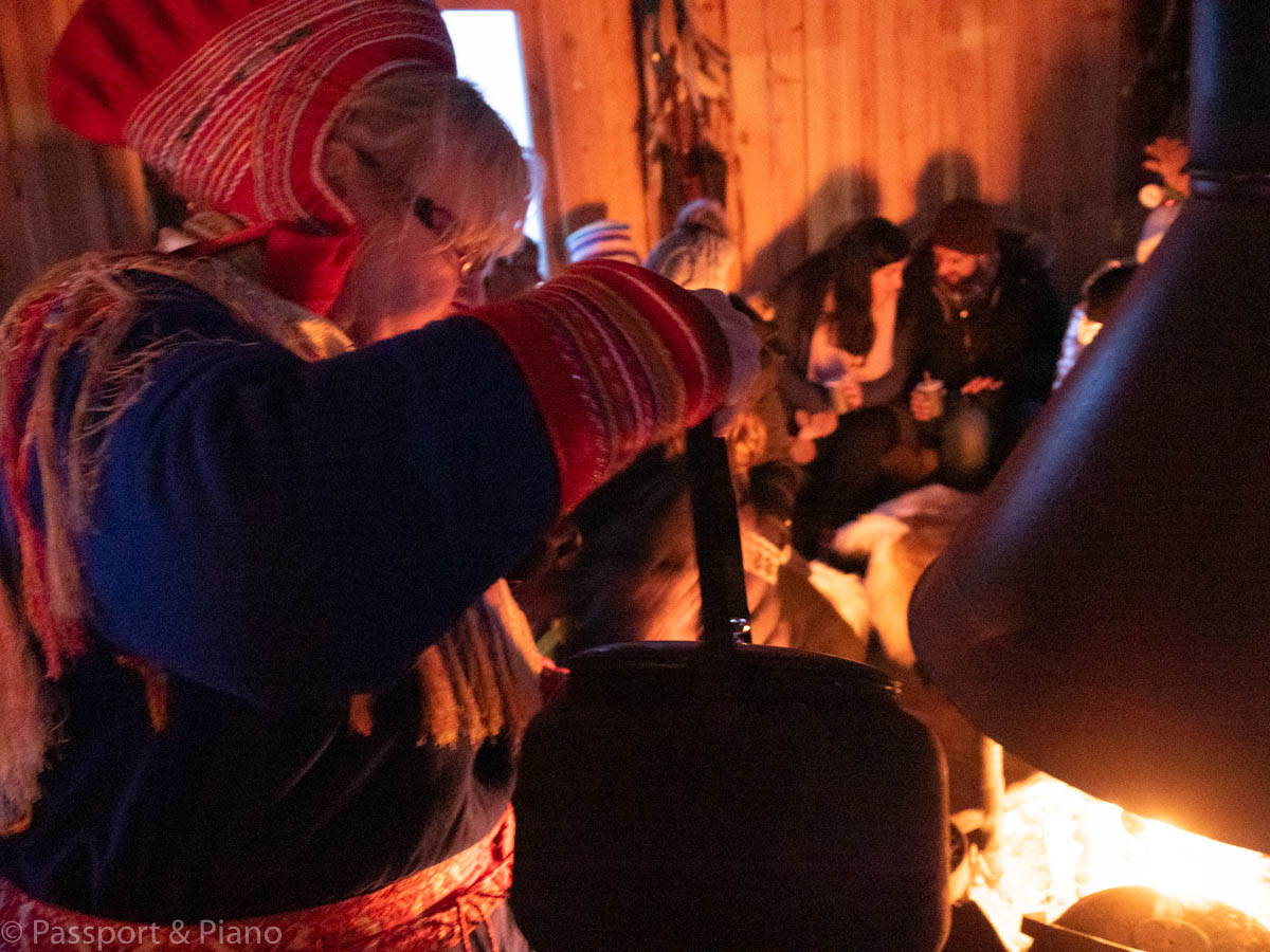 An image of a Sami woman in traditional dress pouring tea in tromsø winter