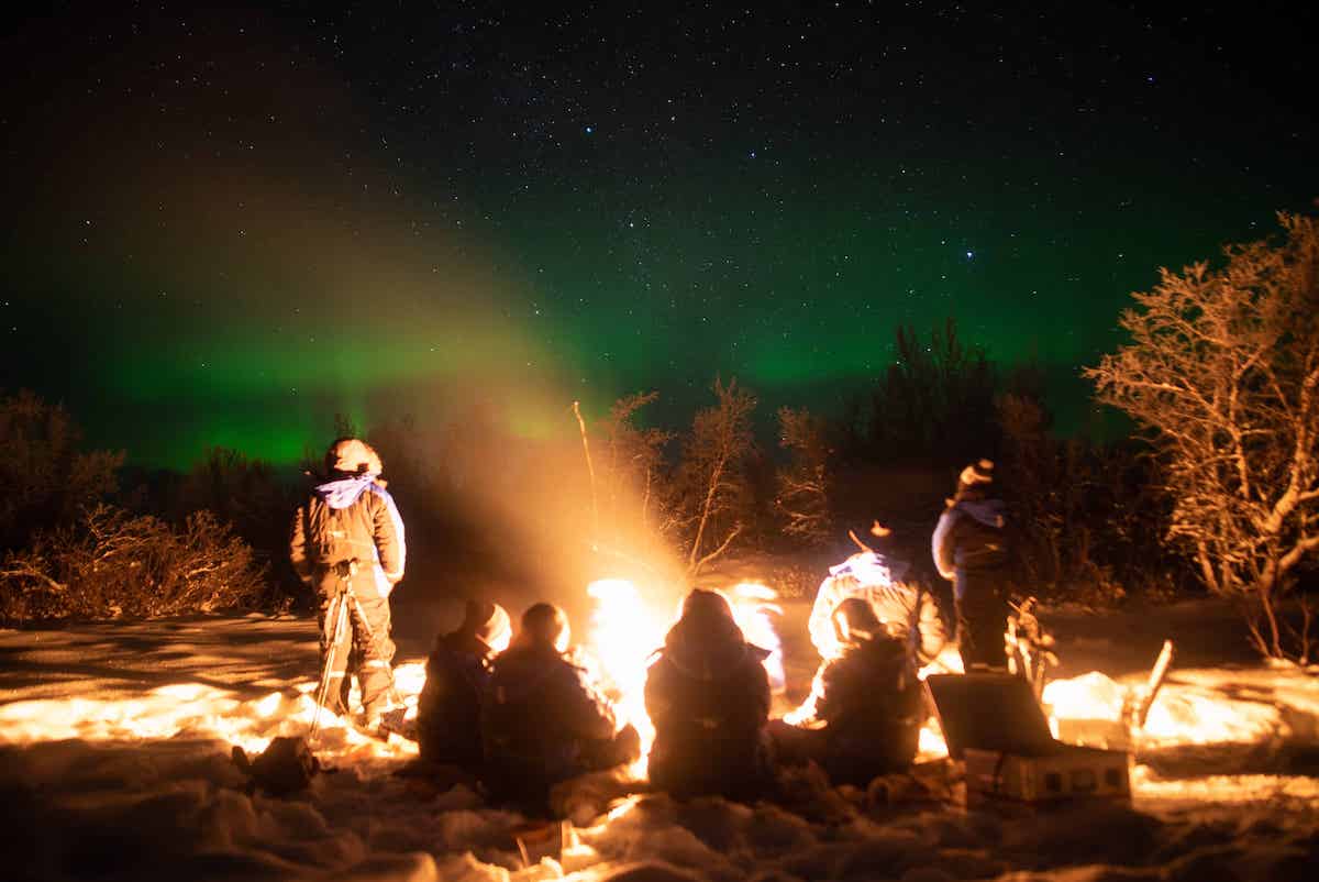An image of a campfire with chasing lights at Lake Kilpisjarvi