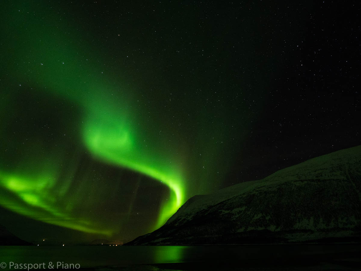 An image of the green swirl of the northern lights with a mountain in the foreground