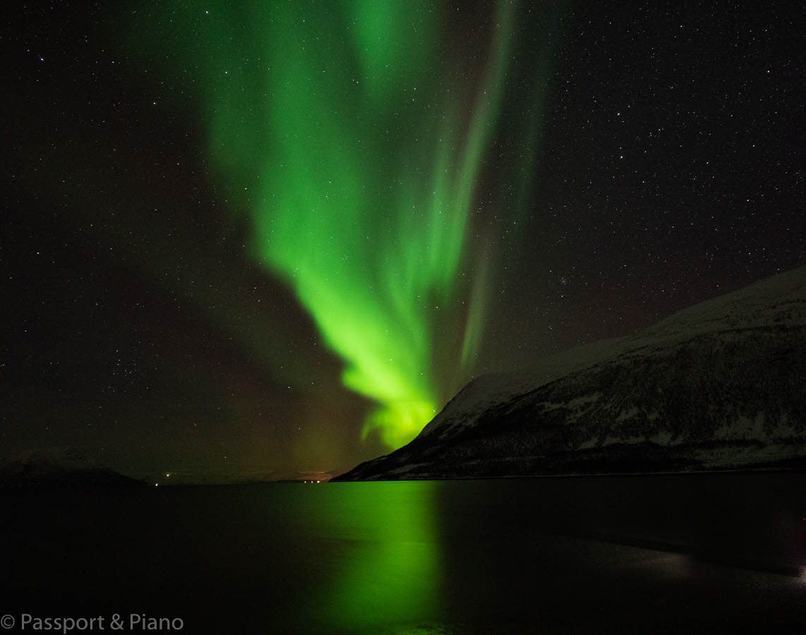 An image of a strong bright green Aurora behind a mountain near Tromso, Norway